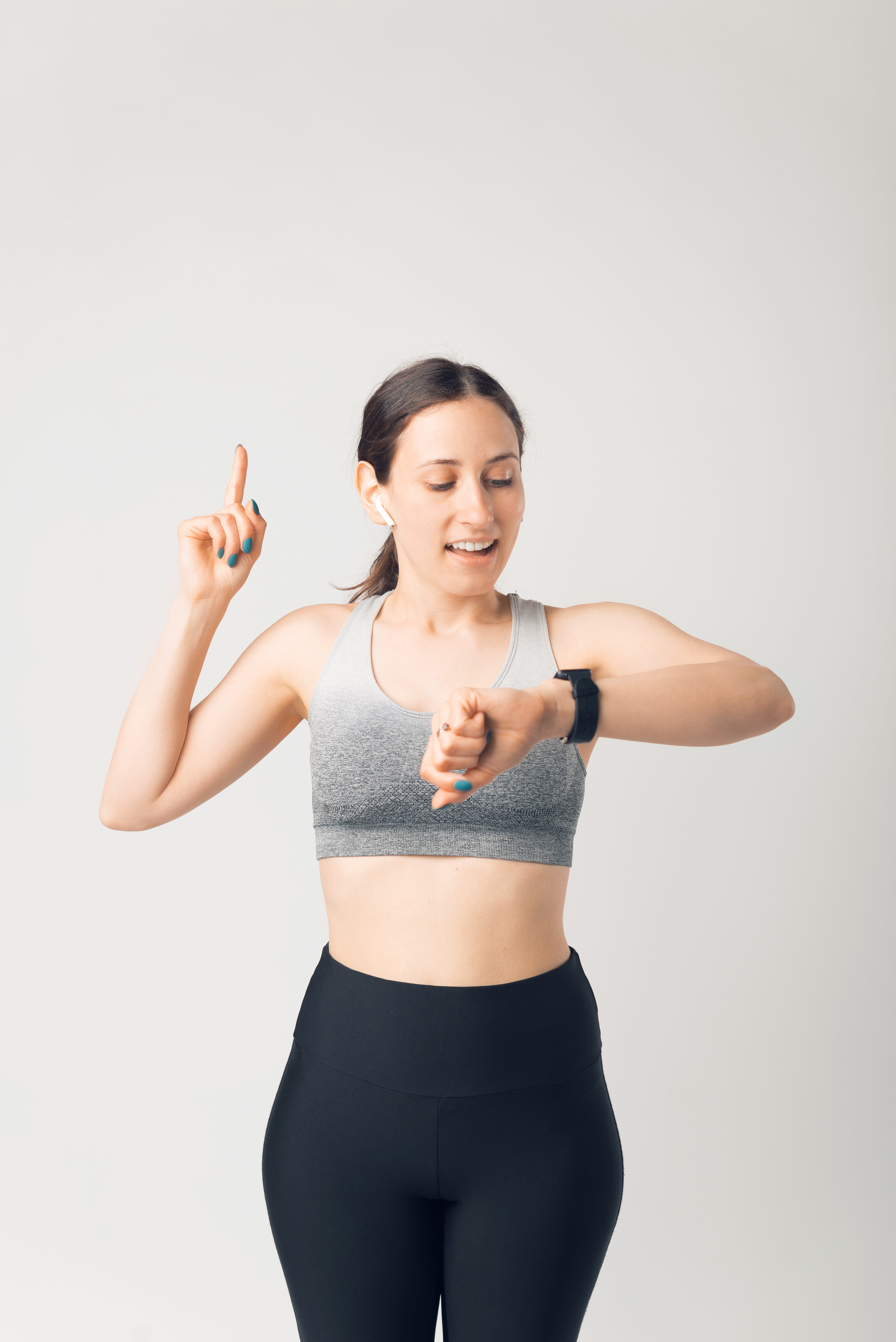 sporty-young-woman-looking-smartwatch-pointing-up-white-background.jpg